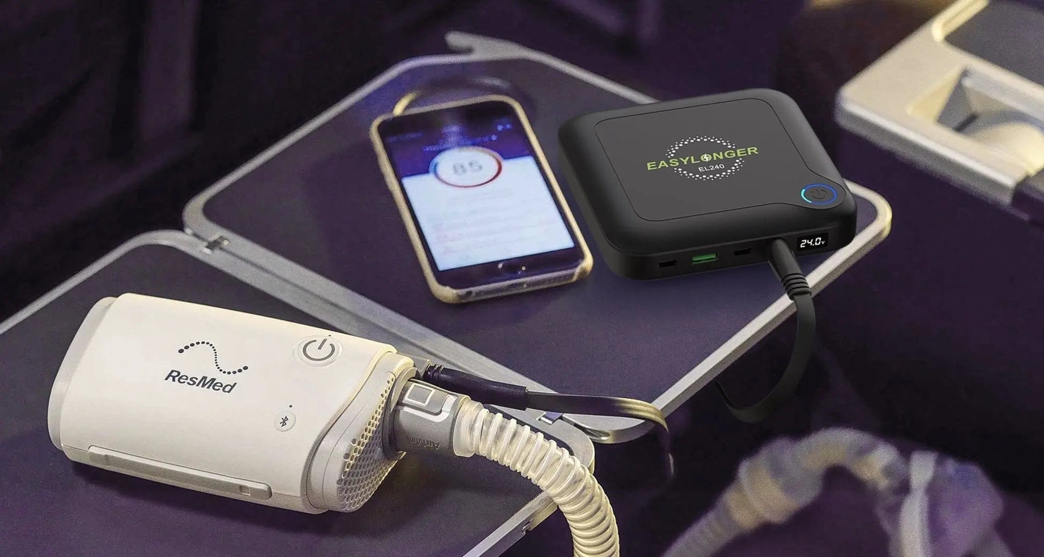 EASYLONGER ES400 AIR portable power bank connected to a CPAP machine and a smartphone on an airplane tray