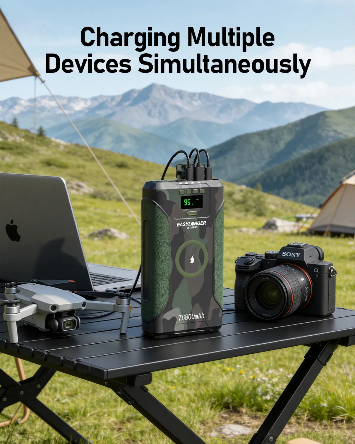 An EASYLONGER ES720 PRO Camo CPAP Battery Pack charges a laptop, camera, and drone outdoors on a black table. The screen shows charging details, with tents and mountains in the background—perfect for camping or as a CPAP battery backup.