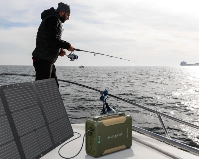 A person stands on a boat fishing, using a portable power station and solar generator set up on the deck. The boat is on open water, with other boats visible in the distance.