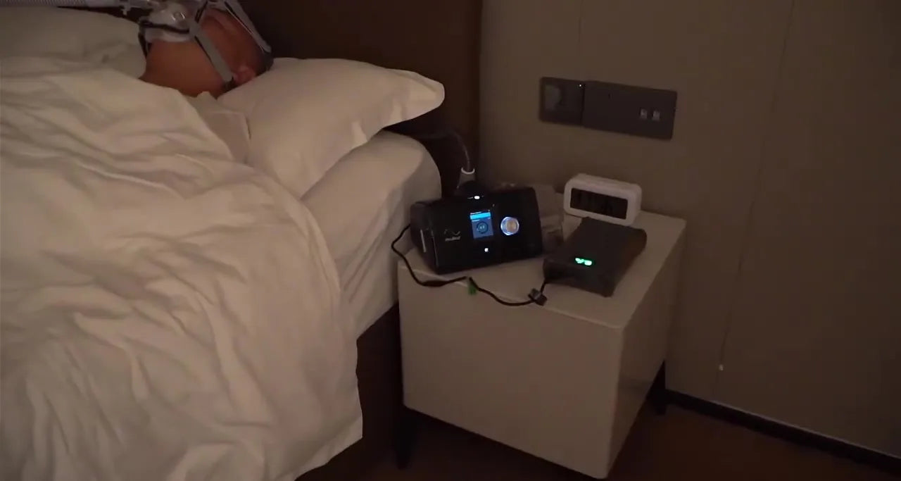 A CPAP running on an EASYLONGER battery on a hotel nightstand